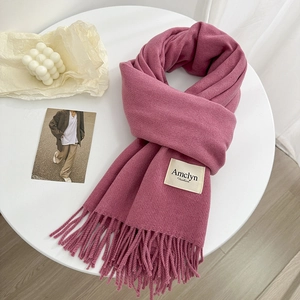 Détail d'une écharpe douce en laine mélangée rose foncé avec franges et étiquette tissée