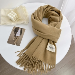 Détail macro de l'écharpe en mélange de laine camel avec franges et étiquette tissée