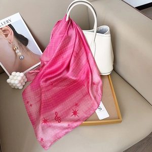 Y2K gradient silk scarf with musical notes tied to a chic leather handbag