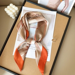 Détail d'un carré de soie avec motifs géométriques orange et texte All My Life brodé