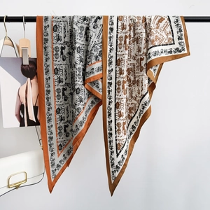 Detail of elegant carriage print silk scarf draped over a black rack with vintage pattern