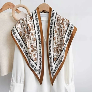 Classic horse carriage pattern silk scarf in white and brown hung on a wooden hanger