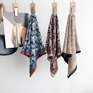 Three silk scarves with paisley pattern in navy, burgundy, and camel hanging elegantly