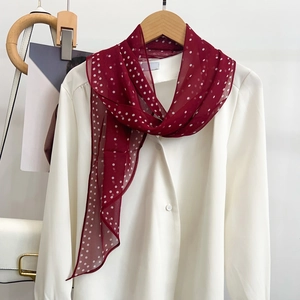 Classic red silk scarf with white polka dots tied on a white shirt with a wooden hanger
