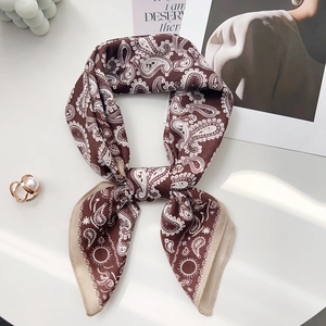 Detailed view of coffee brown paisley silk scarf tied in an elegant bow on a table
