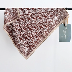 Classic paisley silk square scarf in dark coffee brown hanging on a black bar