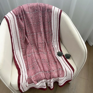 Dettaglio della sciarpa in cotone bordeaux con stampa paisley su divano bianco