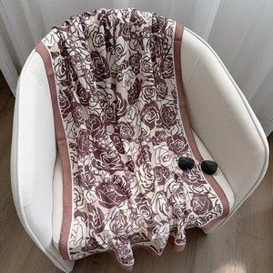 Detail shot of elegant floral linen scarf with rose and chain patterns on a white chair