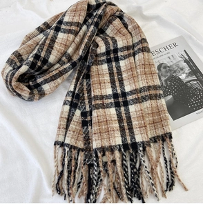 Detail of classic plaid scarf with long fringe on a soft white knitted background