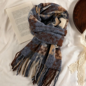 Close-up of blue and brown checkered scarf with long fringe and thick knit texture