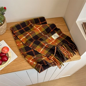 Detail of retro plaid scarf with fringe in orange and green on a wooden surface