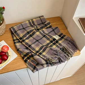 Detailed view of thick plaid scarf with purple yellow patterns and long tassels decor