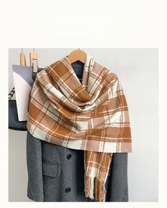 Détail du motif à carreaux marron et blanc et des franges d'une écharpe d'hiver douce