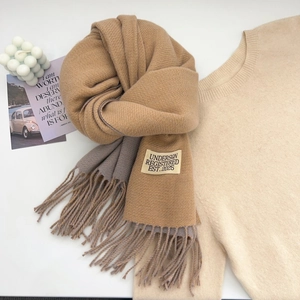 Detailed texture of thick camel and grey cashmere-like scarf with soft tassels and woven tag