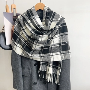Écharpe classique à carreaux noirs et blancs avec franges sur un manteau en laine gris