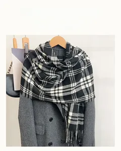 Detail of black and white checkered scarf with fringe tassels on grey winter coat