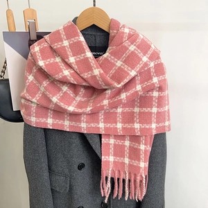 Pink and white plaid winter scarf with tassels displayed on a grey wool coat