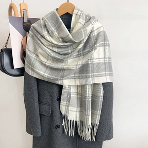 Détail d'une écharpe à carreaux gris et blanc avec texture douce en cachemire et franges