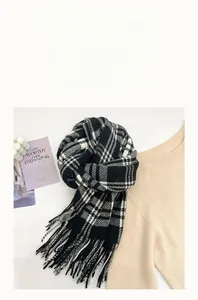 Detail of cashmere-like black and white plaid scarf with soft tassels for winter