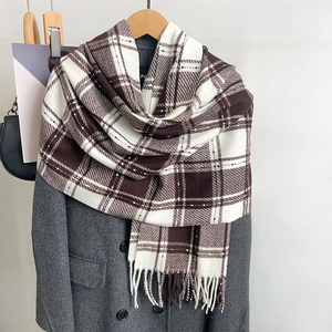 Détail de l'écharpe d'hiver à carreaux marron et blanc avec des franges sur un manteau