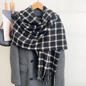 Detail of black and white checkered scarf with soft fringe on a wool coat
