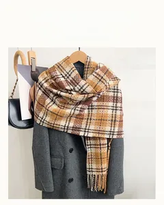 Detail of vintage plaid scarf with soft tassels hanging on a hanger with grey coat
