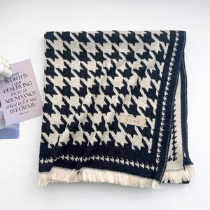 Detail view of houndstooth scarf with soft fringe and stylish leather label detail