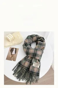 Detail of soft green plaid cashmere scarf with fringes and elegant brand label