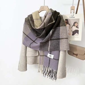 Close-up of purple plaid scarf featuring long tassels and a woven brand label detail