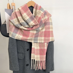 Close-up of soft pink and blue plaid winter scarf texture with handmade tassels