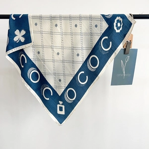 Detail of elegant blue and white square silk scarf with COCO lettering and floral pattern