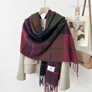 Detail shot of vintage plaid tassel scarf in deep red and green on a tweed coat
