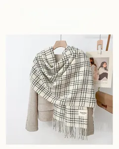 Detail of checkered autumn scarf with fringe on beige blazer and lifestyle props