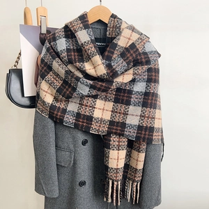 Detail of plaid tassel scarf with soft wool texture styled on a dark gray pea coat