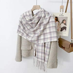 Detail of purple and beige plaid scarf with tassels on a light wool coat outfit