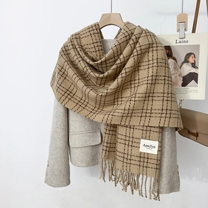 Detail of camel plaid scarf texture with elegant fringes styled on a grey wool coat