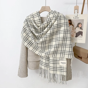 Classic black and white checkered scarf with fringe on a cozy beige wool coat