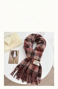 Detail of red-brown checkered faux cashmere scarf with fringe on a white table