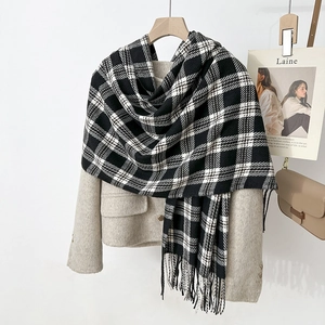 Gros plan d'une écharpe à carreaux noirs et blancs avec franges sur manteau beige