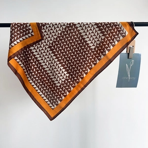 Dettaglio di un foulard in seta con motivo geometrico marrone e cuciture fini ai bordi
