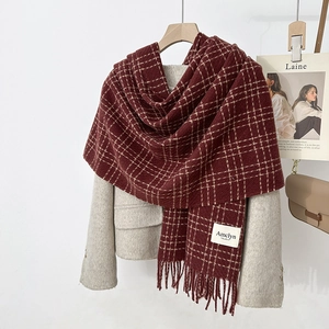 Detail of burgundy checkered scarf with fringe trim and premium brand label texture