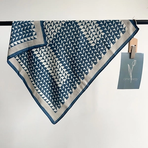 Dettaglio del motivo geometrico a ventaglio blu navy e grigio sul raffinato foulard quadrato