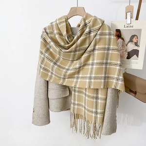 Détail d'une écharpe à carreaux beige avec de larges franges et une texture d'hiver douce
