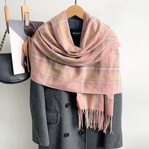 Détail d'une écharpe à carreaux rose et jaune avec des franges sur un cintre