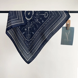 Navy blue paisley and key print silk scarf hanging on a black rod against white wall