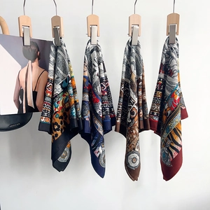 Detail view of silk leopard print scarves hanging on a wooden rack with a chic bag