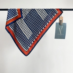 Dettaglio di un foulard geometrico con bordi arancioni e motivi a ventaglio blu navy