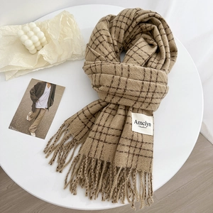 Classic camel checkered winter scarf with fringes and minimalist brand label on desk