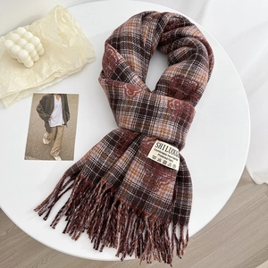 Cozy checkered cashmere-like scarf with tassels, styled on a white decorative platter