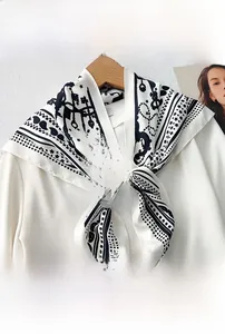 Detail of a white silk triangle scarf with black paisley and star patterns on a hanger
